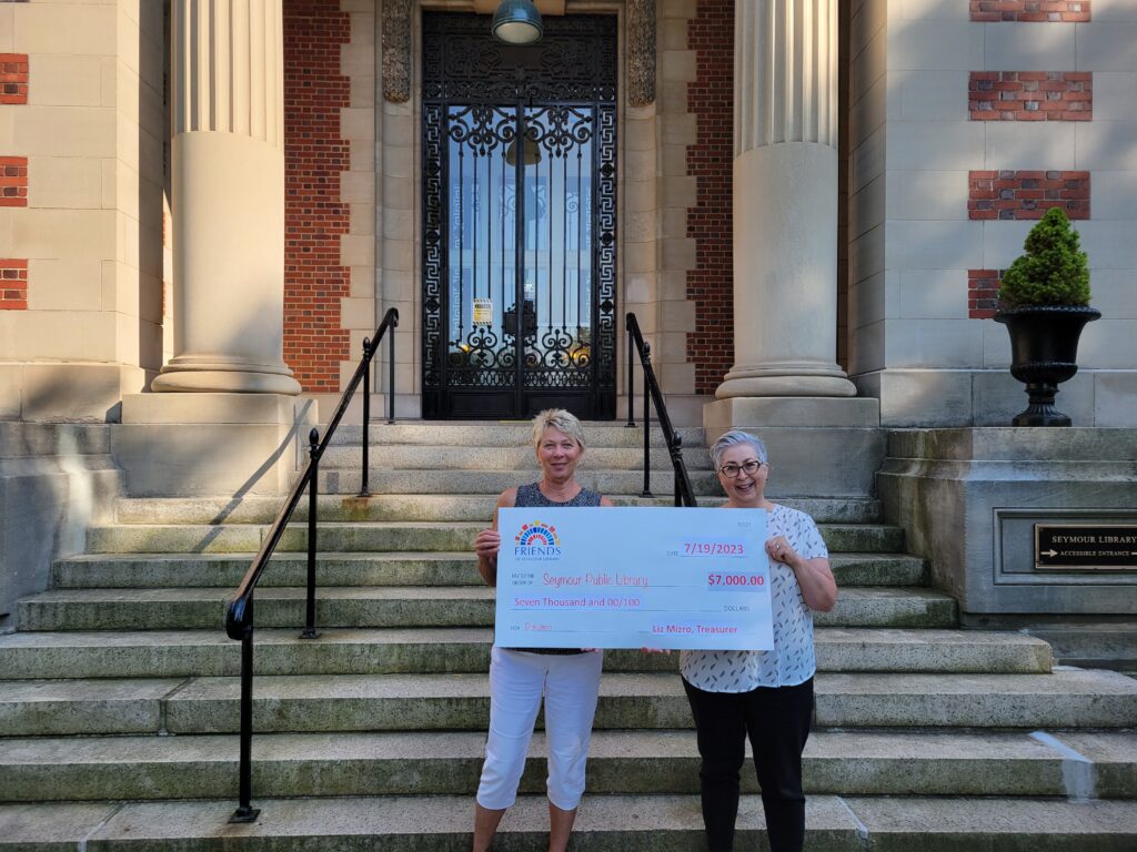 Image of two individuals holding a check for $7,000 at the stairs of Seymour Library.