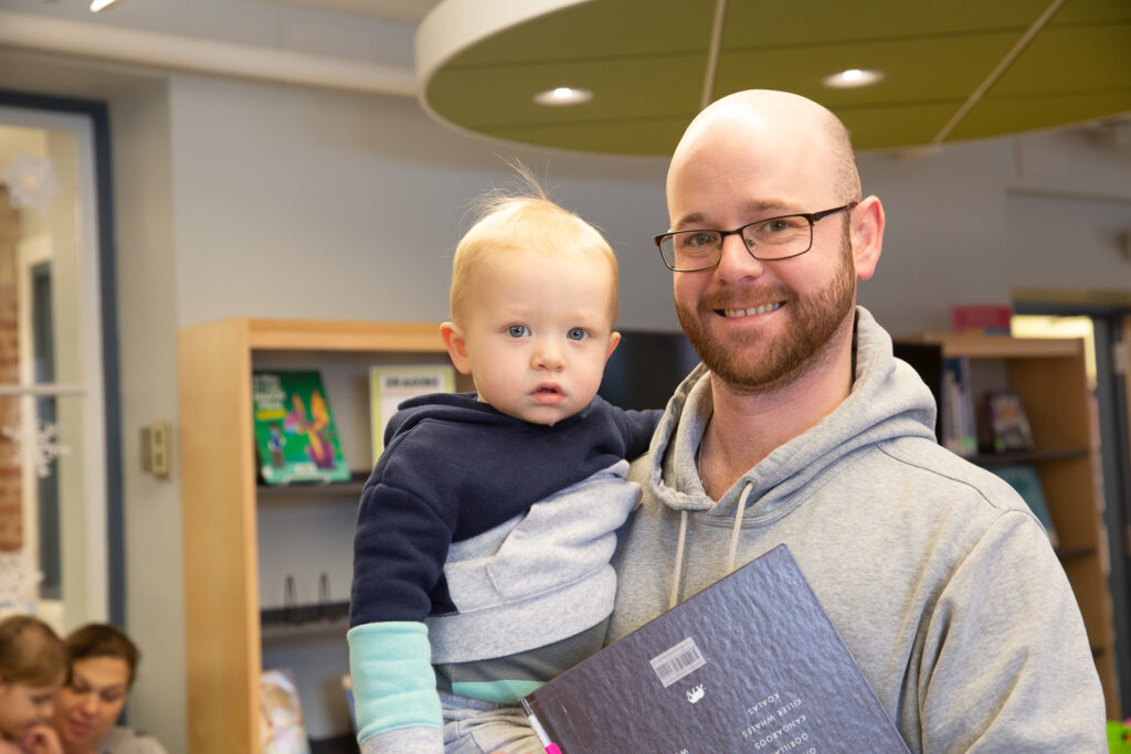 Winter Break in the Family Space - Parent and their child holding a book at a Seymour Library Storytime.
