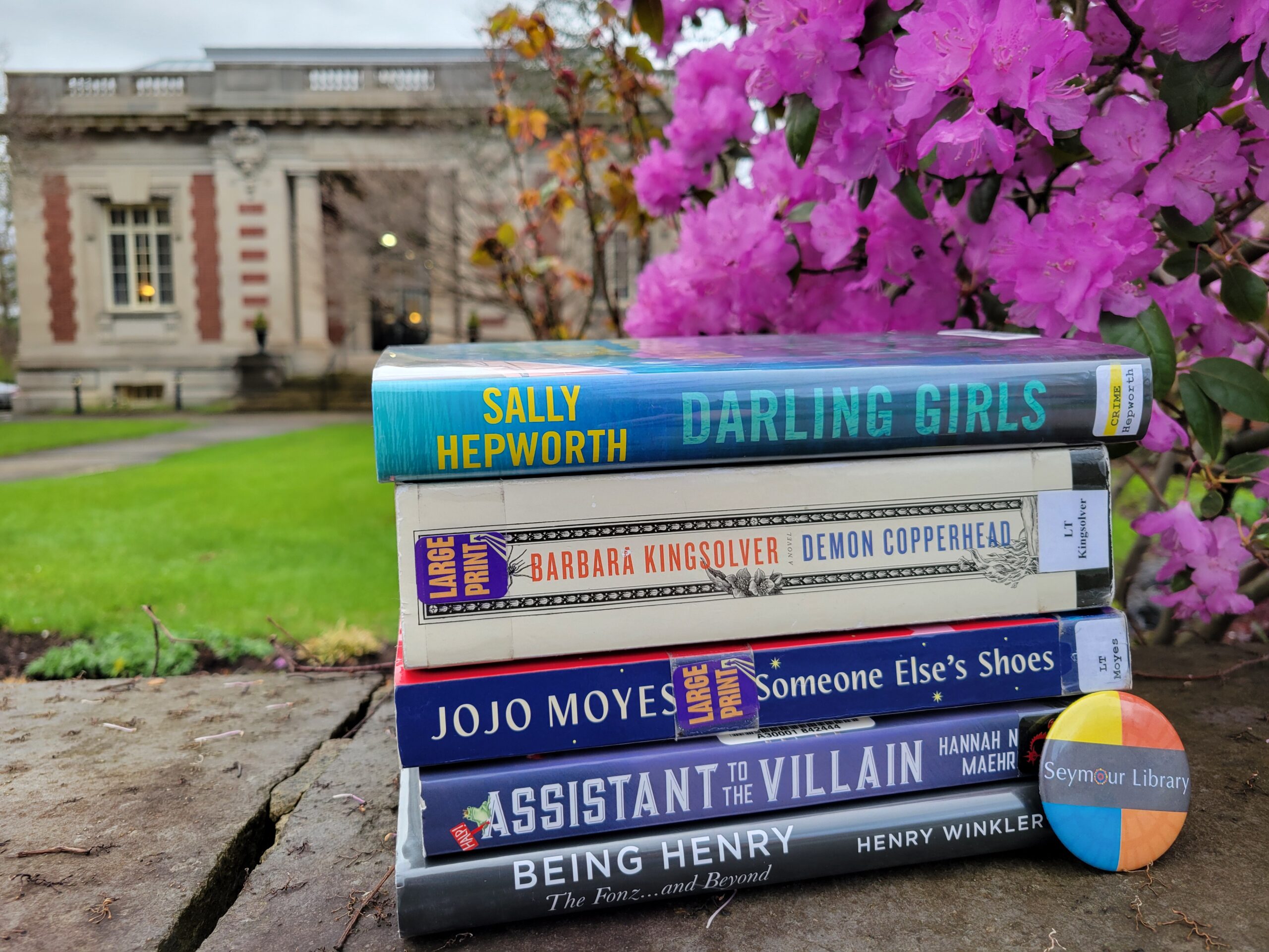 Get Caught Reading -- Seymour Library Staff Picks -- 2024. Image features stack of books in front of the historic Seymour Library.